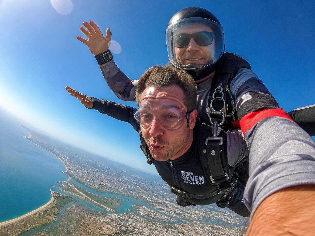 Tandem skydivers in freefall high above the Algarve coastline